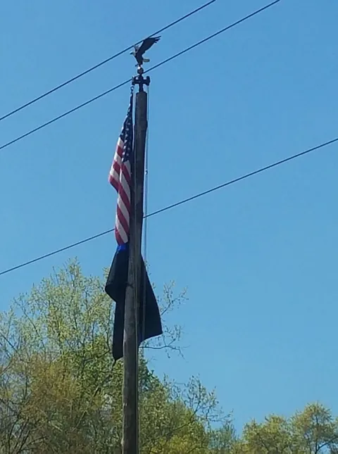 An American flag flying on a wooden pole against a clear blue sky
